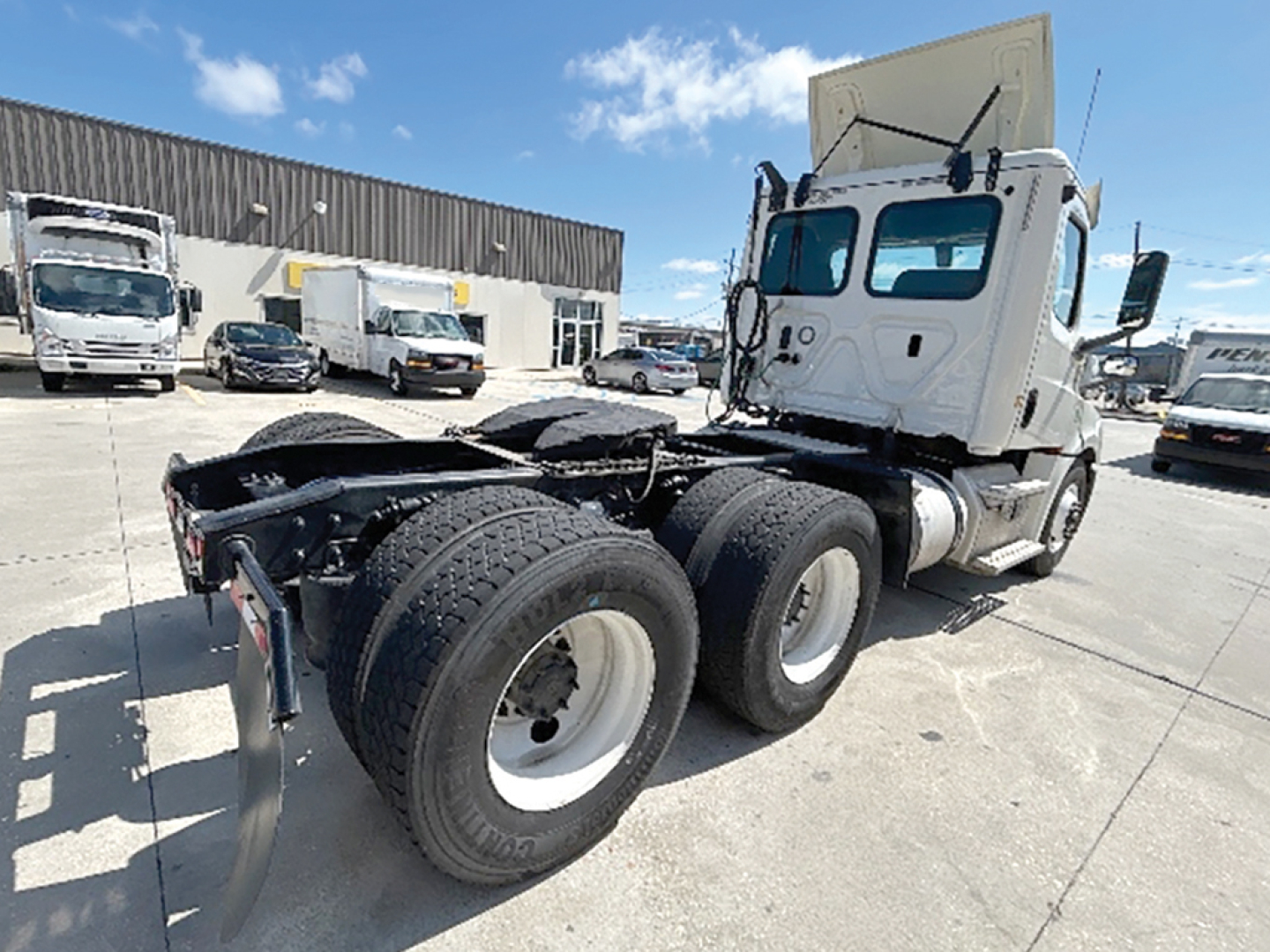 Freightliner Cascadia 126 tractor at a dealership, rear three-axle configuration with dual rear wheels, white cab, visible VIN and stock number in listing context.