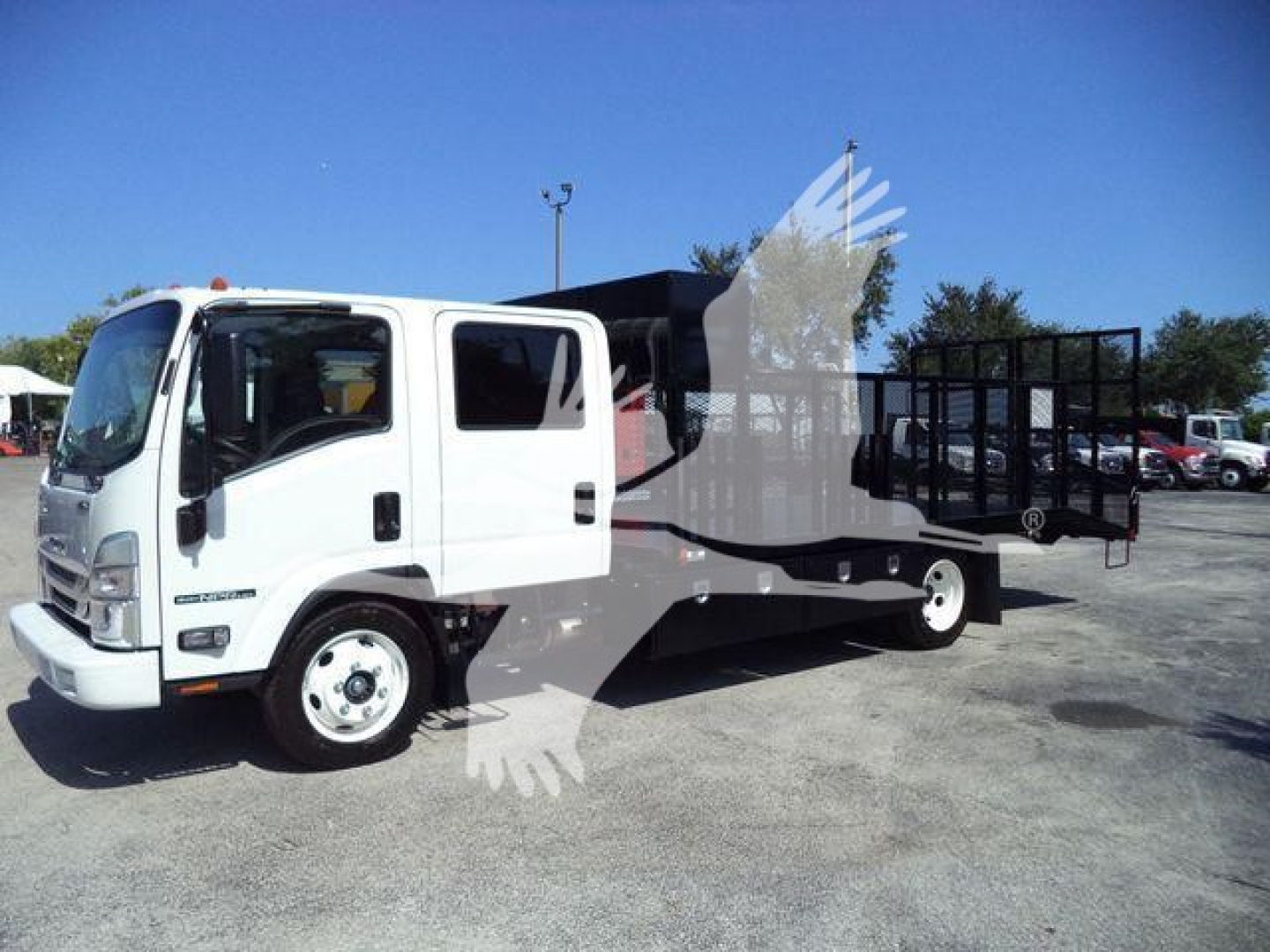 White Isuzu NPR-HD cab and flatbed tow truck profile in a lot, stock number NPRLANDSCAP visible in listing.