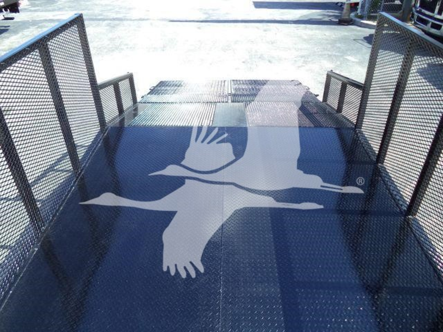 Isuzu NPR-HD flatbed truck bed with metal side rails and decorative bird logo on the glossy surface