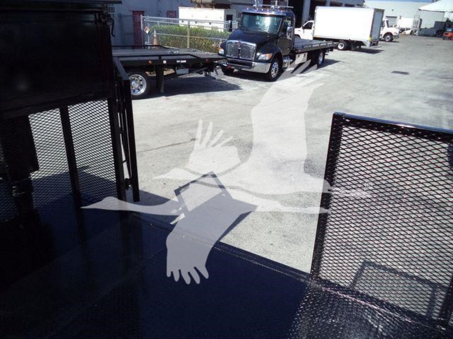 Isuzu NPR-HD truck bed area with metal railing and reflection of vehicles in background.