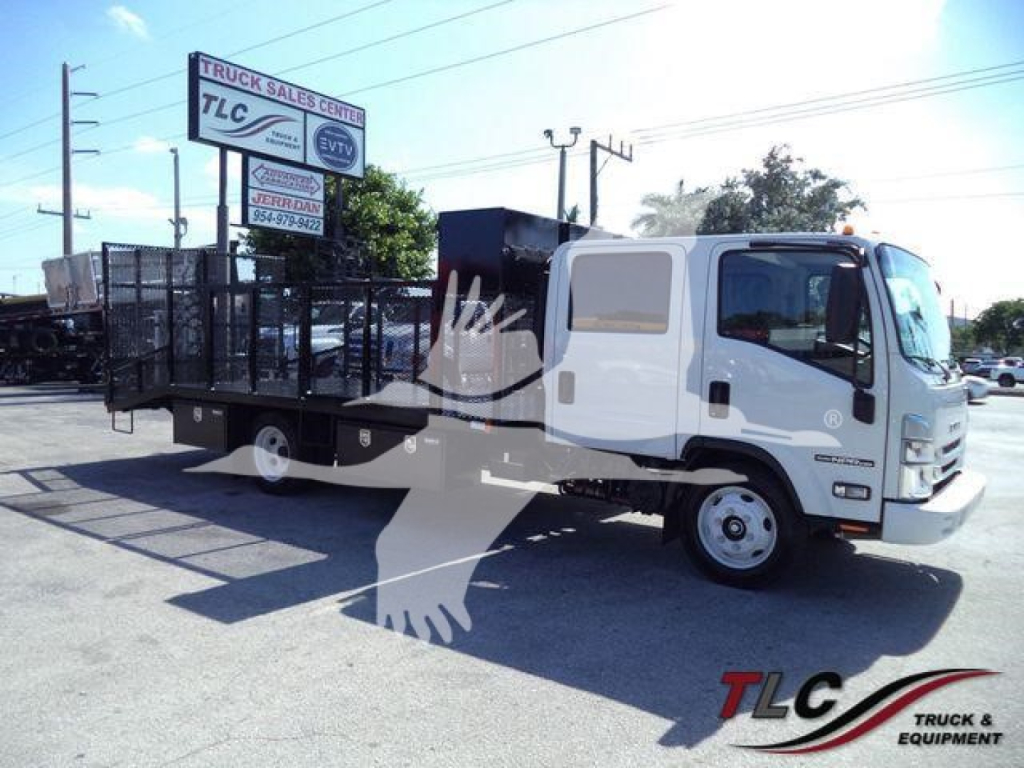 Isuzu NPR HD truck with a long flatbed and utility cages on the bed, side view showing cab and driver door, light-colored truck in a dealership lot
