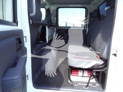 Isuzu NPR-HD cargo area interior with seating and seating belts visible, empty rear cabin, compact storage, fire extinguisher mounted near floor.