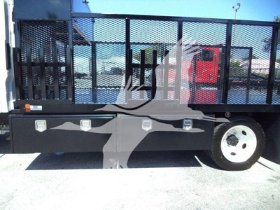 Isuzu NPR-HD truck bed area with storage boxes and metal stake body side panel, partial wheel visible.