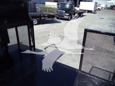 Isuzu NPR-HD truck bed area with metal railing and reflection of vehicles in background.