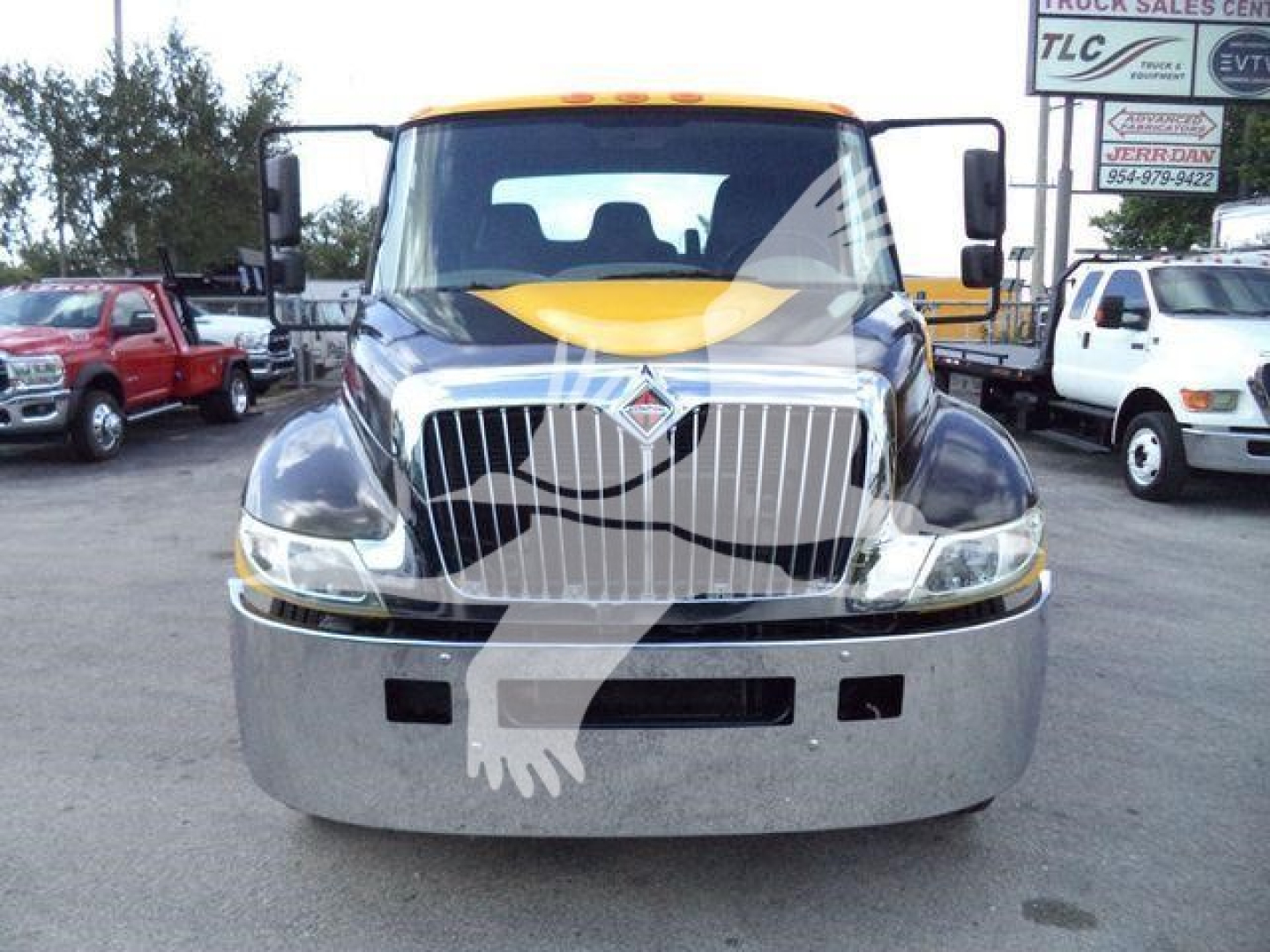 Truck front view of a 2019 International 4300 in a used rollback truck listing showing the chrome grille, bumper, and headlights.