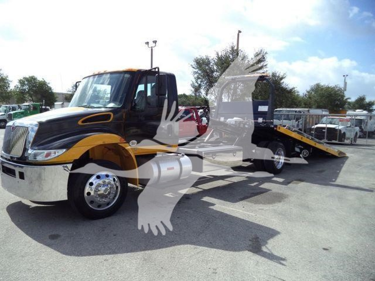 2019 International 4300 rollback truck in service position with tow bed extended, black and yellow color scheme, chrome front bumper, stock number T82488FM.