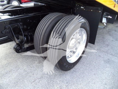 Truck axle and dual rear wheels on a rollback chassis showing dual tires and wheel rims.