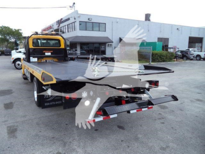 International 4300 rollback tow truck rear view showing hydraulic flatbed and taillights.