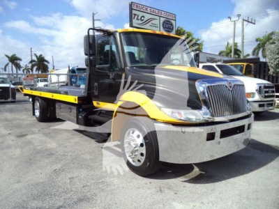 International 4300 rollback truck showing front and left side with yellow and gray paint.