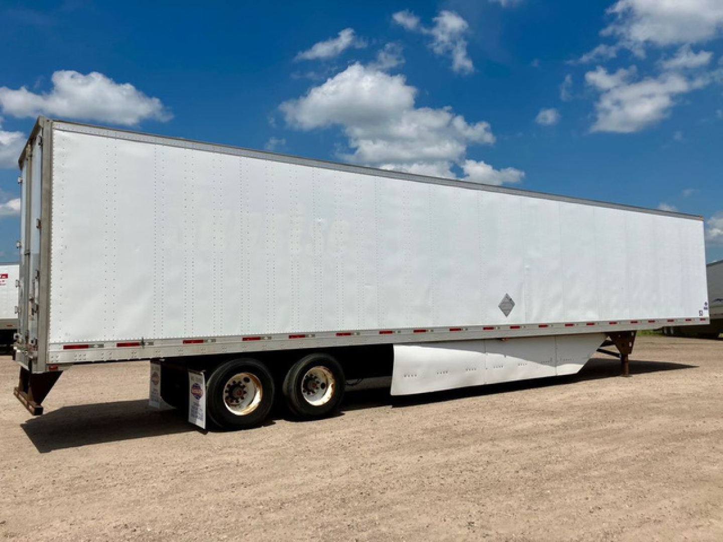 Trailer van showing side view with white box trailer and dual rear axles, no visible branding or text.