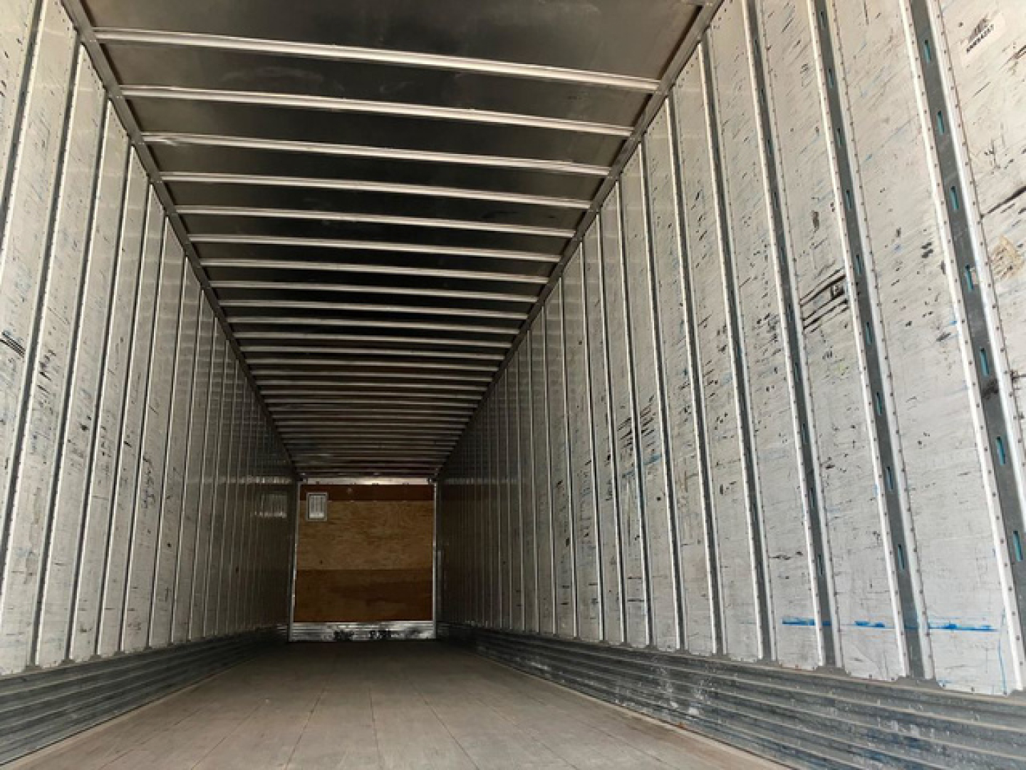 Trailer interior showing long aluminum walls and ribbed ceiling, empty cargo space in a utility van trailer.