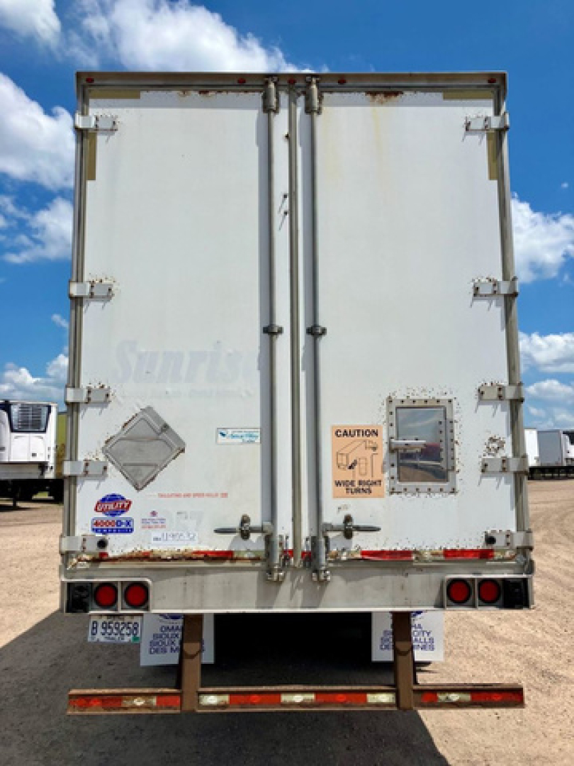 Rear view of a white utility van trailer with double doors, CAUTION label, and warning window on right door.