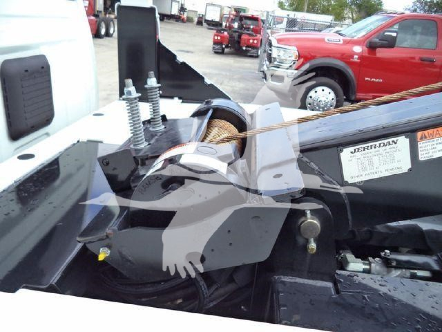 Winch-equipped Ram 4500 truck bed view showing hydraulic reel and control components with warning label and spring-loaded pins