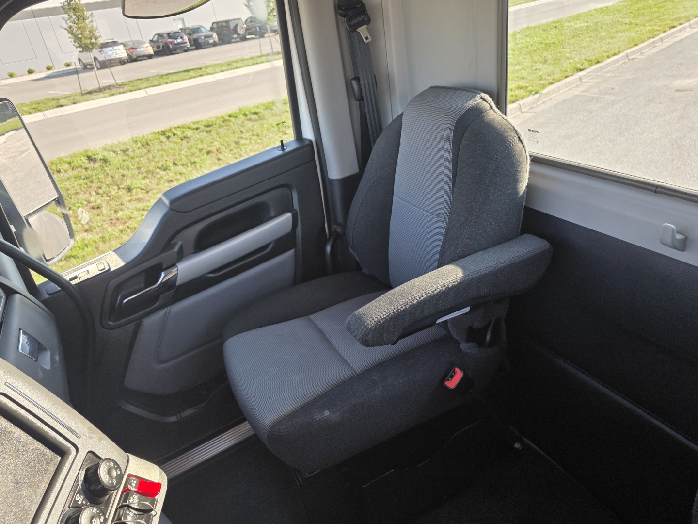 Kenworth T680 cab interior showing driver seat and door panel; dashboard and steering wheel not fully visible.