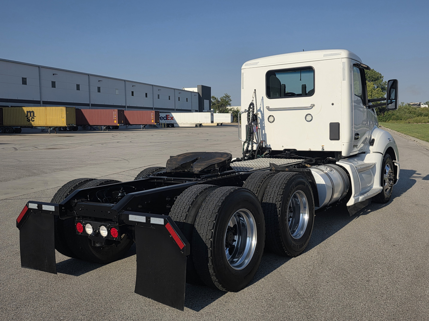 Kenworth T680 daycab tractor seen from rear three-quarter view showing fifth wheel, dual rear axles, and fuel tanks; no visible text on components.