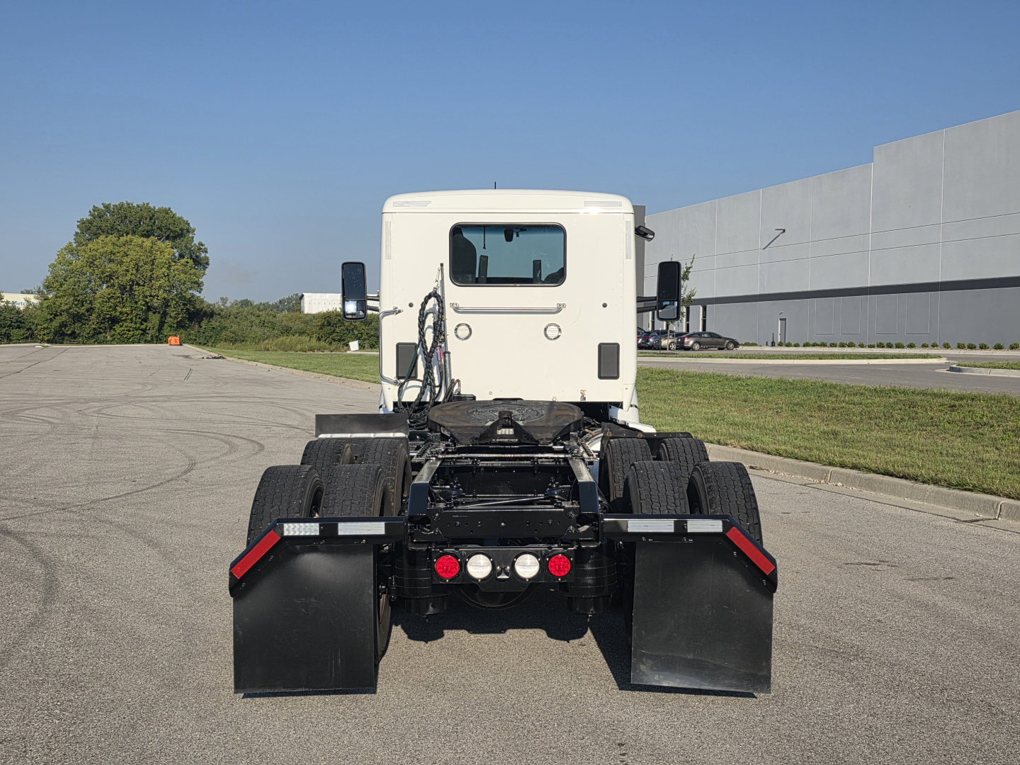 Kenworth T680 rear view showing chassis, dual rear axles, and fifth wheel attachment points with mud flaps.