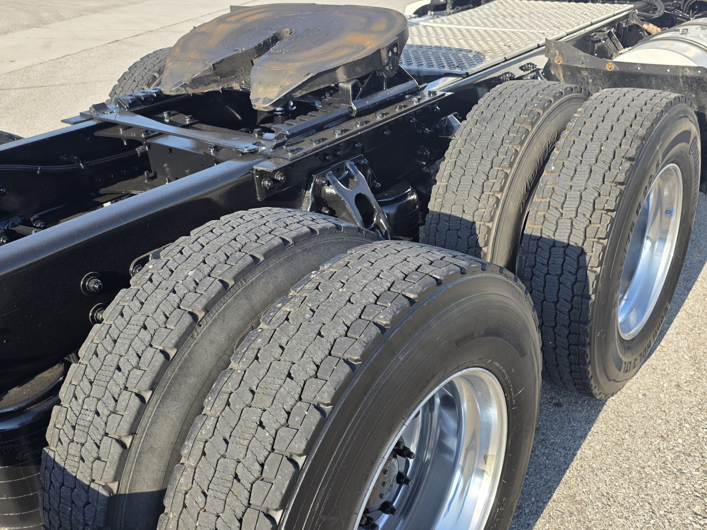 Kenworth T680 chassis rear view showing triple-axle arrangement with dual rear tires and fifth wheel plate.