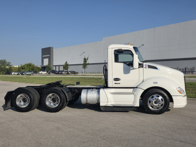 Kenworth T680 conventional daycab tractor in white side view showing cab, fuel tanks, and dual rear axles with chassis visible.