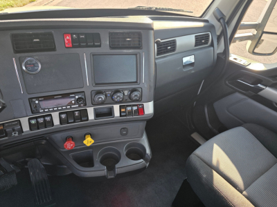 Kenworth T680 dashboard and front cabin view showing steering area, center console with controls, and driver seat.