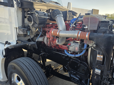 Kenworth T680 engine bay showing turbo hoses and red diesel engine with metal piping and black frame.