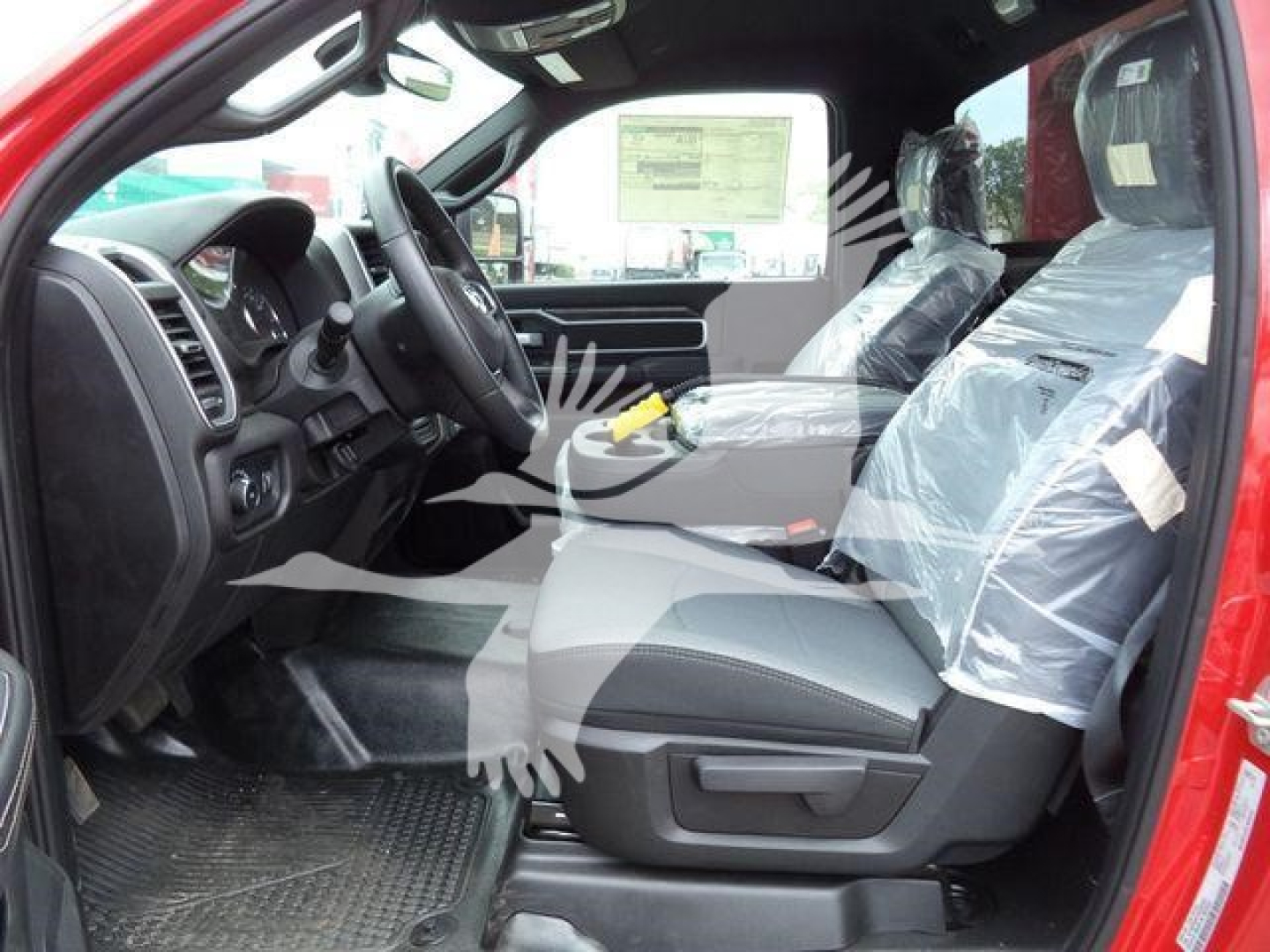 Ram 4500 SLT interior view from open driver door showing front seats wrapped in protective plastic, dashboard, steering wheel, and center console.