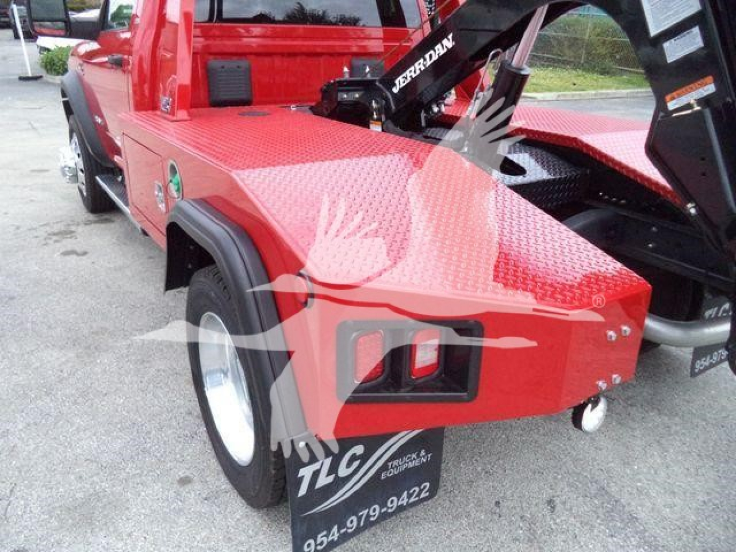 Ram 4500 tow truck bed area showing red diamond-plate deck, fender, and winch arm with TLC branding visible.
