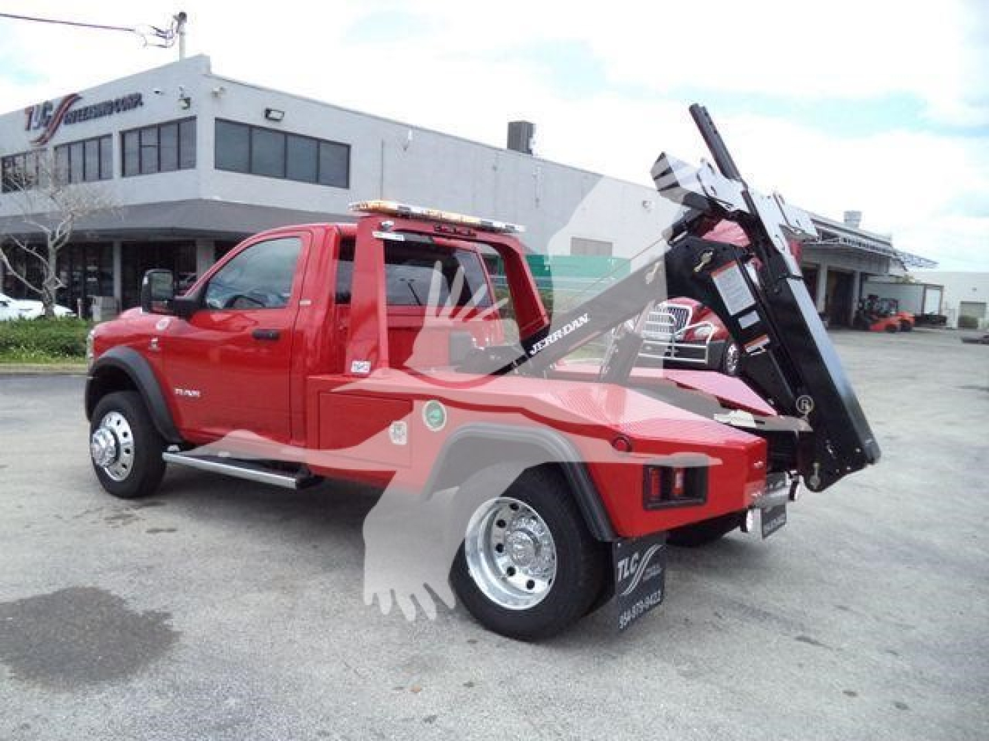 Ram 4500 tow truck with black hydraulic bed in raised position, red cab, in-service view showing side profile and loading equipment.