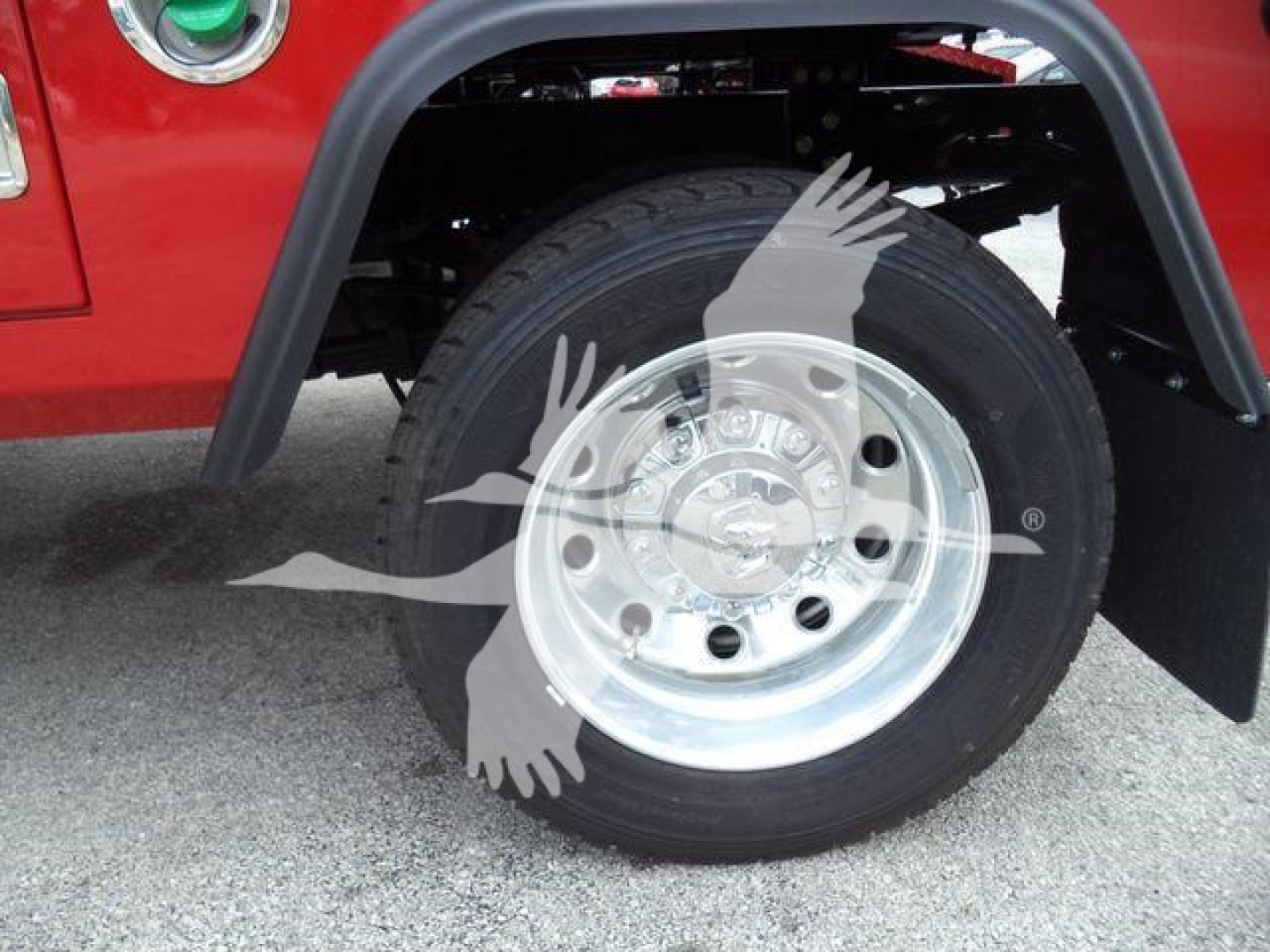 Truck wheel well with chrome wheel and tire, red fender and black fender flare visible.