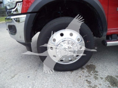 Truck wheel showing chrome hubcap on front left wheel with red fender and black tire.