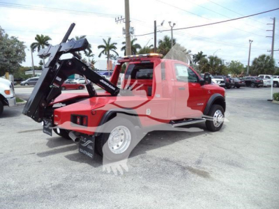 Ram 4500 SLT pickup with a heavy-duty rear winch and hydraulic lift on a dealership lot; red cab with black equipment, showing a winch mount and truck bed components.