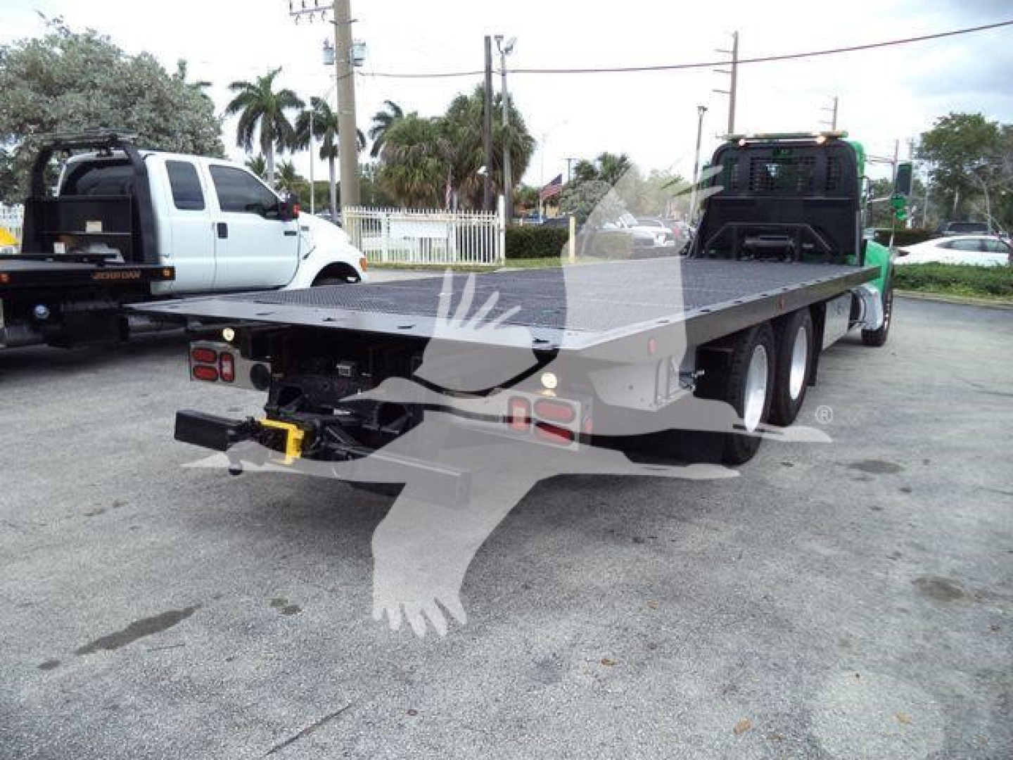 Flatbed tow truck chassis of a 2016 Peterbilt 348 rollback showing rear and flatbed with dual rear axles and towing hitch.