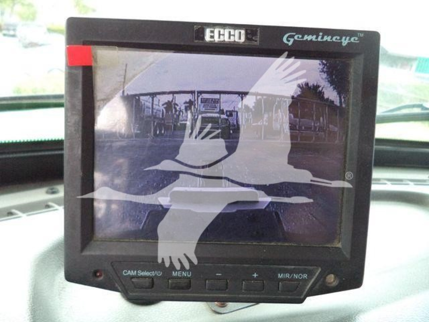 In-vehicle monitor display showing a live camera feed with the Ecco Gemincye branding and control buttons below; view appears inside a Peterbilt rollback truck cabin.