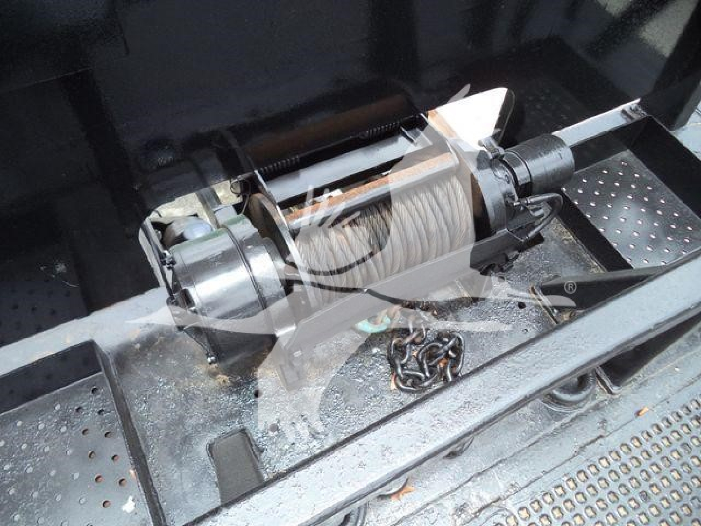 Winch assembly with cable drum and hydraulic winch in truck bed showing steel roller fairlead and mounting bracket.