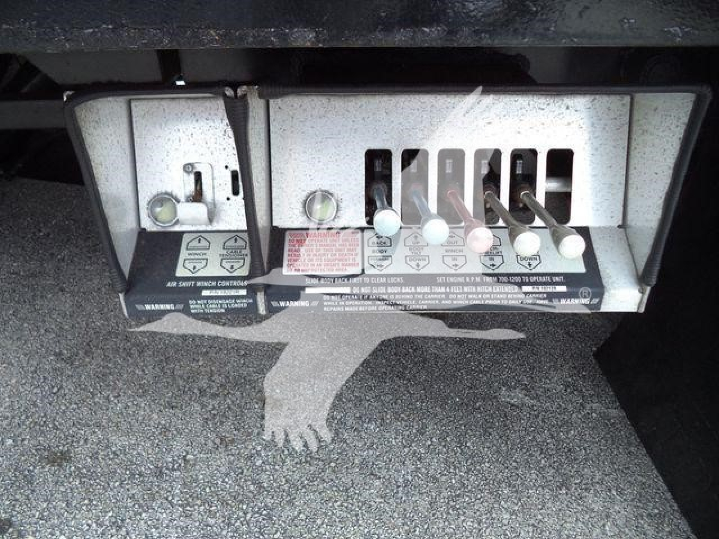 Panel with levers and switches on Peterbilt truck control box; labels and warning stickers visible with multiple white levers and a numeric scale.