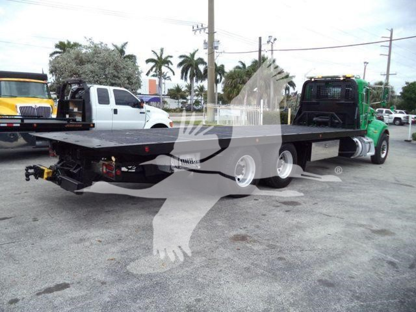 Peterbilt 348 rollback truck flatbed with dual rear axles and a green day cab, shown from rear-left side.