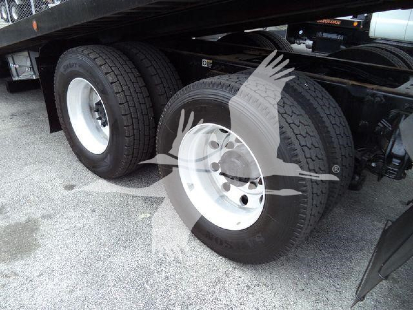 Peterbilt 348 truck chassis with dual rear axles and white steel wheels, viewed from side under a rollback bed.