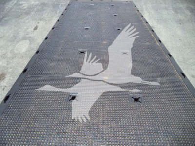 Flatbed rollback truck deck with a large stylized bird graphic in light gray on a metal surface.