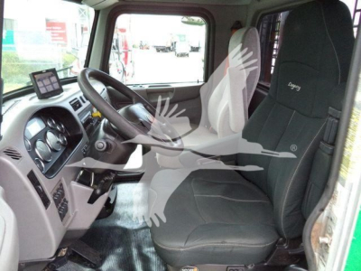 Interior of a 2016 Peterbilt 348 cab with steering wheel, dashboard, and black driver seat; watermark of a bird overlaying the image.