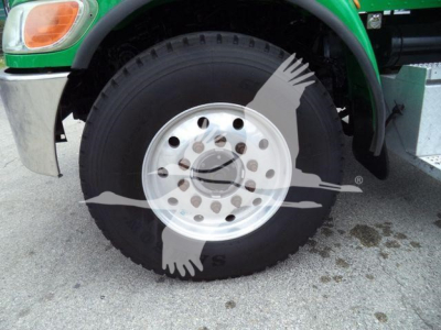 Front wheel and fender of a green Peterbilt truck with a large steel wheel and black tire; watermark with birds overlaid.