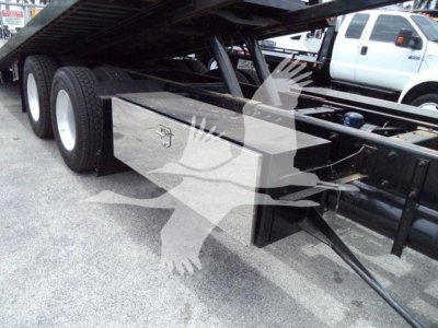 Peterbilt 348 rollback truck undercarriage with a silver metal toolbox mounted under the frame, dual rear wheels, and a raised bed section.