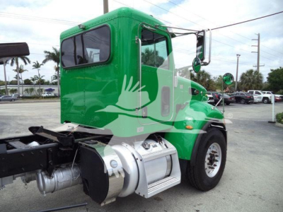 Peterbilt 348 rollback truck in green cab and chrome fuel tanks viewed from side showing cab and wheel.