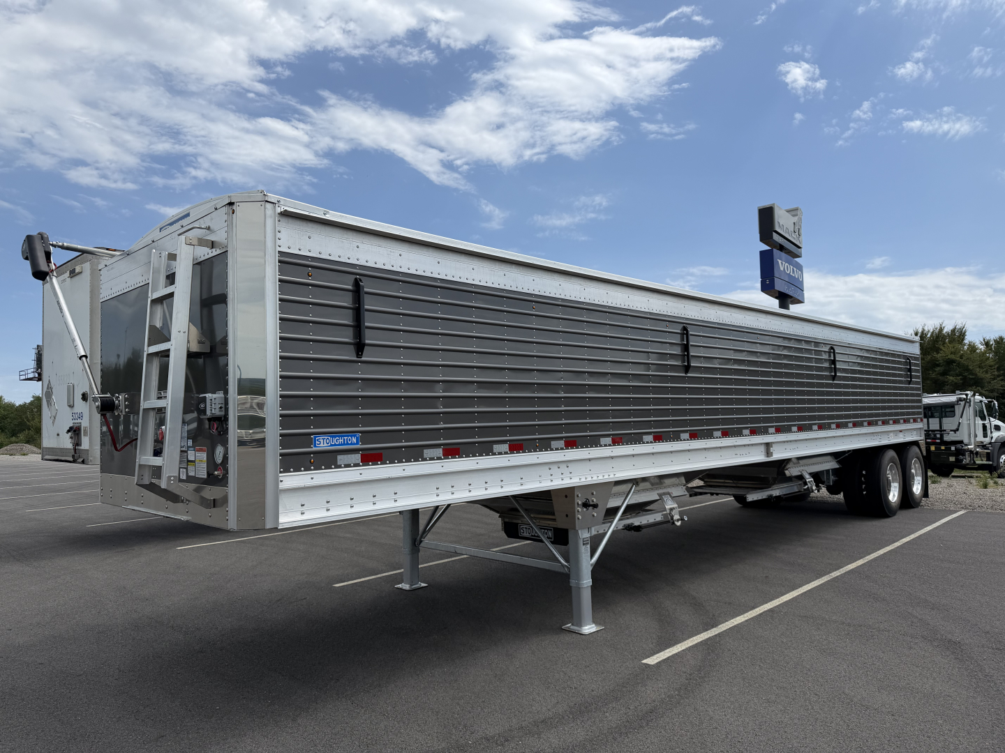 Stoughton 40' aluminum grain hopper trailer with 68-inch corrugated sidewalls, triple-axle configuration, loading chute and ladder visible, side decals and reflective tape along bottom edge.