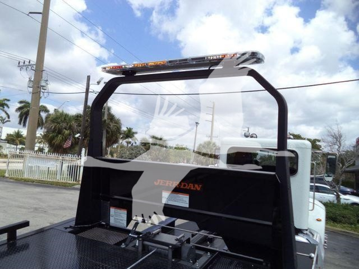 Peterbilt 337 rollback truck cab rear with Jerr-Dan mounting and light bar, windshield, and equipment bed visible.