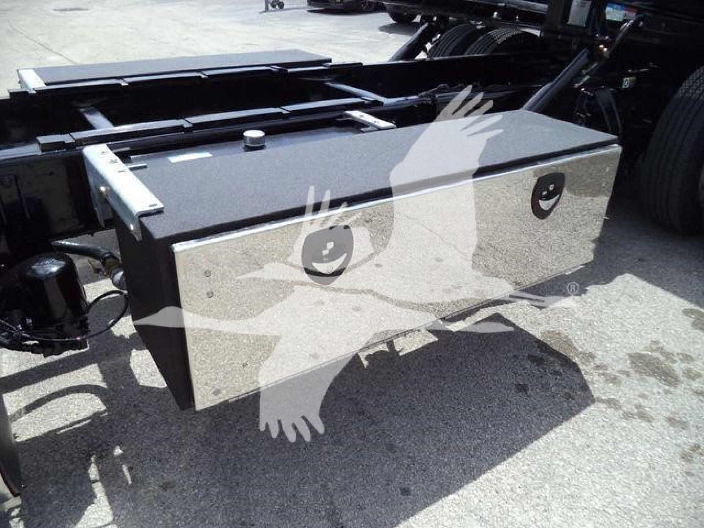 Peterbilt 337 rollback truck with a rectangular aluminum tool box mounted on the chassis showing two circular locks and hinges.