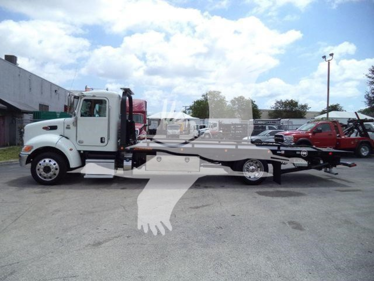 Peterbilt 337 rollback tow truck in side profile with flatbed, white cab, black frame, and loading ramp.