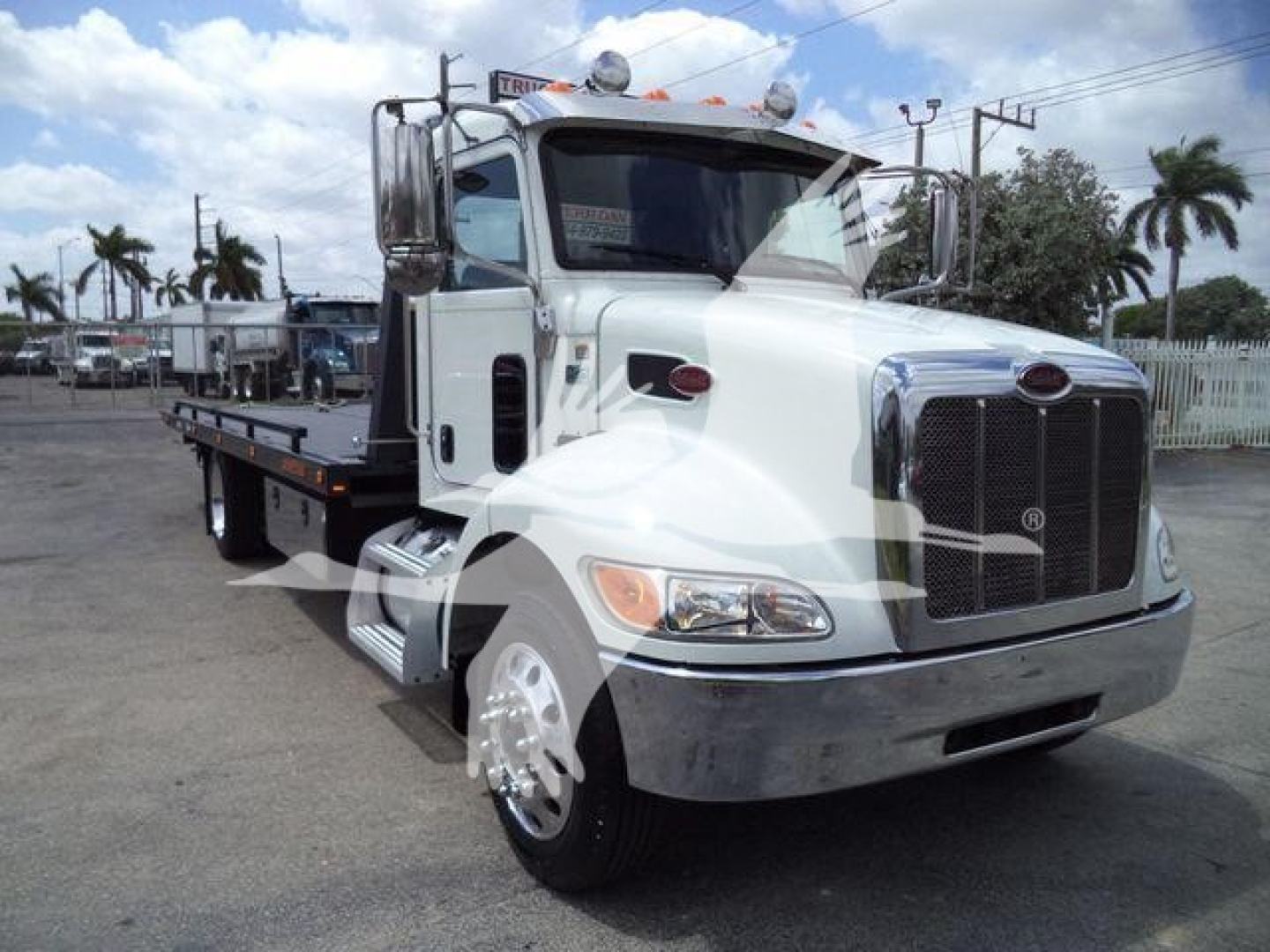 Peterbilt 337 rollback tow truck in white with flatbed, front grille and chrome bumper, side mirrors, and dual rear wheels.