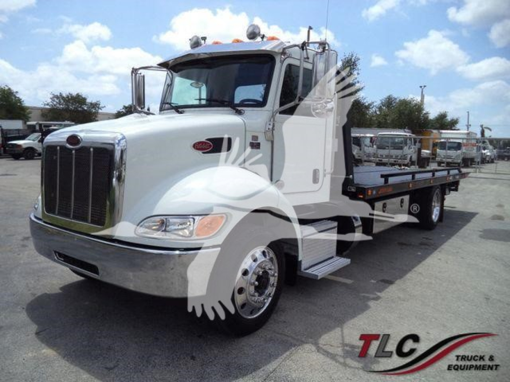 Peterbilt 337 roll-back truck shown from front-left angle with white cab and chrome grille, flatbed with wheel gear, stock photo.