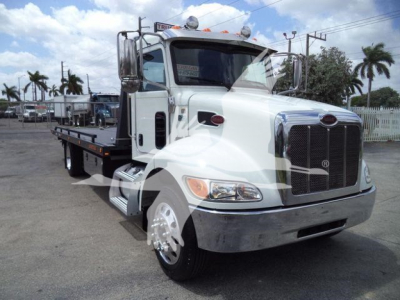 Peterbilt 337 rollback tow truck in white with flatbed, front grille and chrome bumper, side mirrors, and dual rear wheels.