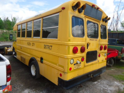 Ford E-450 Thomas shuttle bus rear view with emergency lights, district text along side, rear access door, and license plate visible.