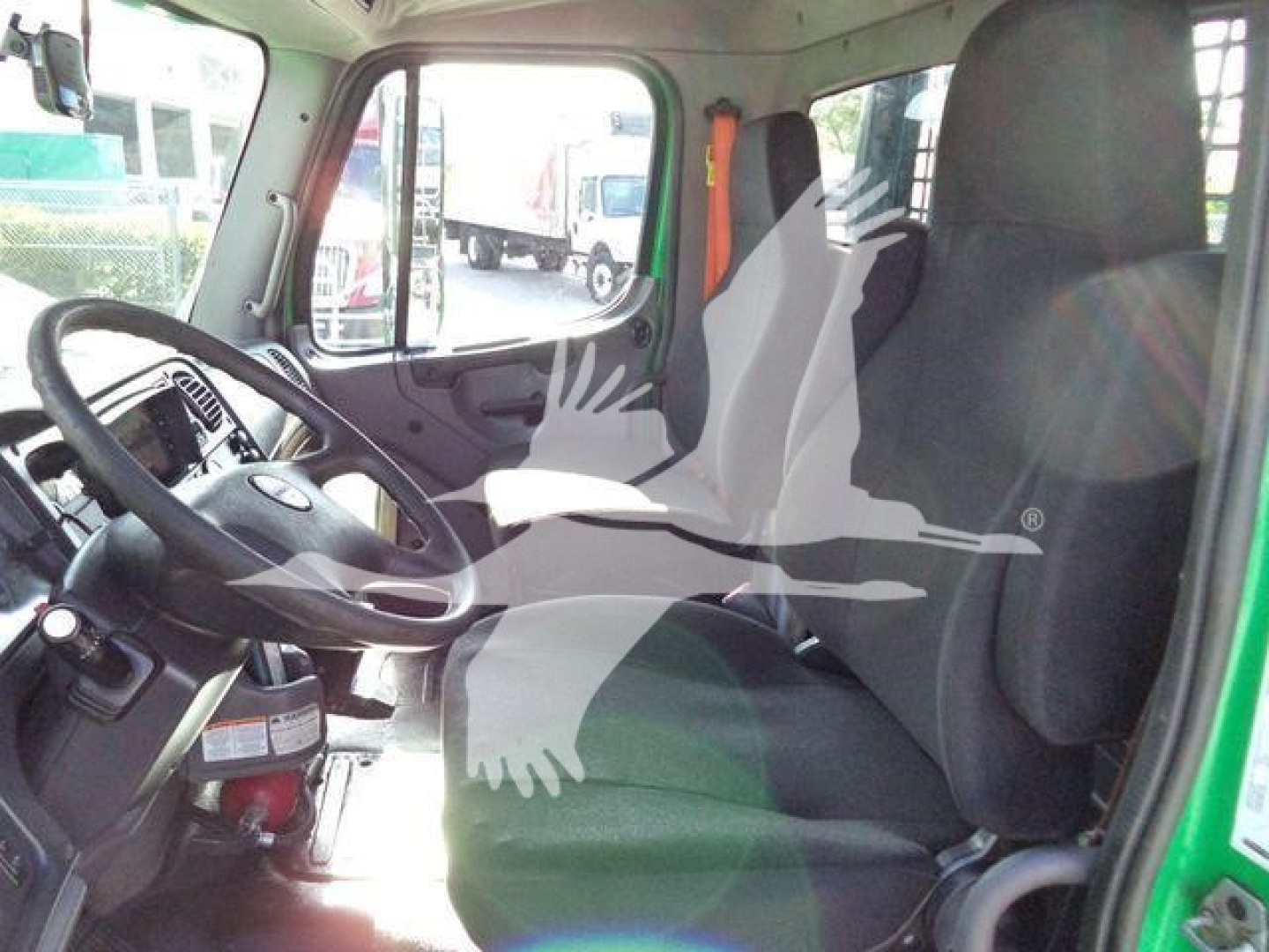 Freightliner M2 106 cab interior with steering wheel, driver seat and passenger seat visible; dashboard area; green exterior door frame